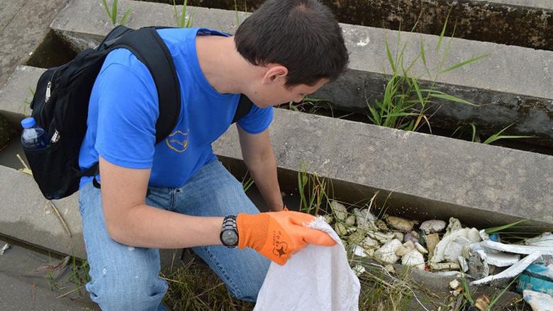 Student picking up trash from the Yantze River in China